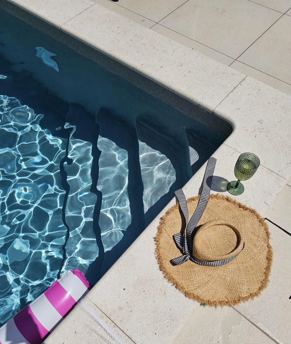 A straw hat and a glass by the pool steps