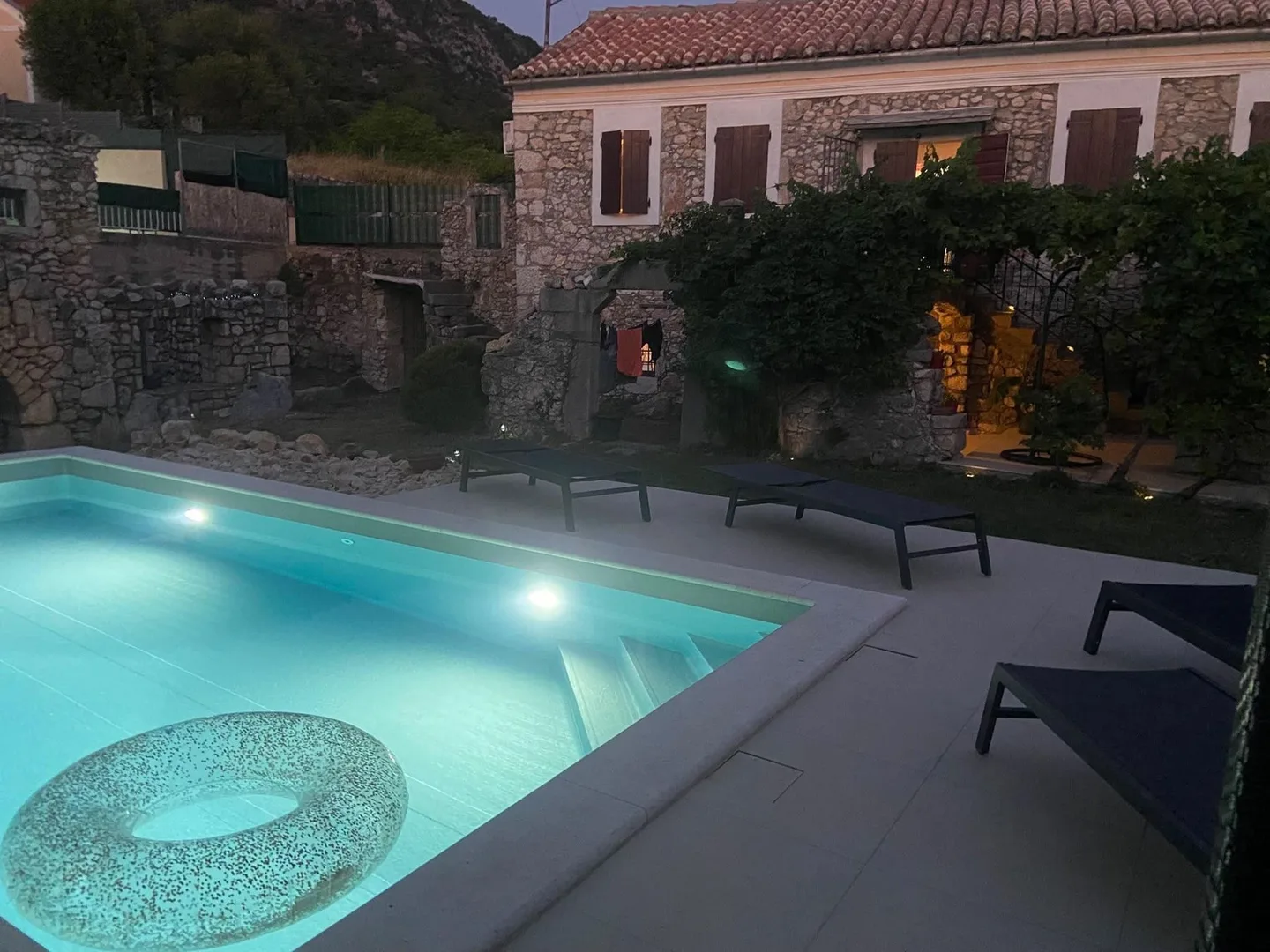 The pool at night, the house and the ruin lit behind it