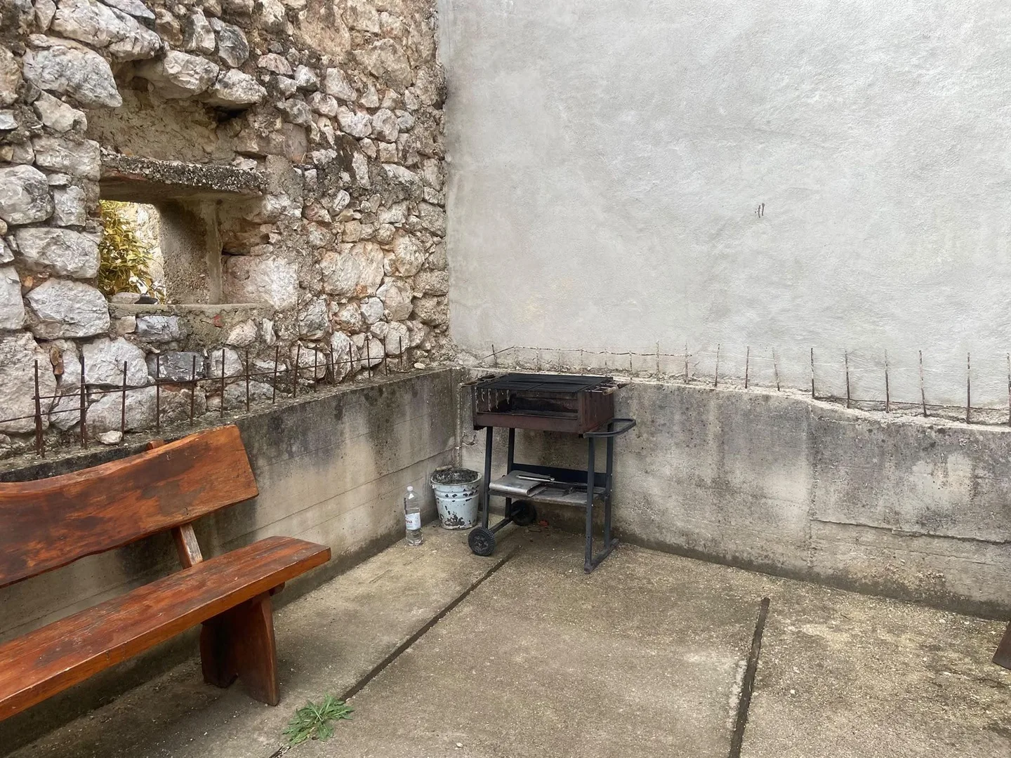 Inside the ruin walls: a wooden bench and a grill