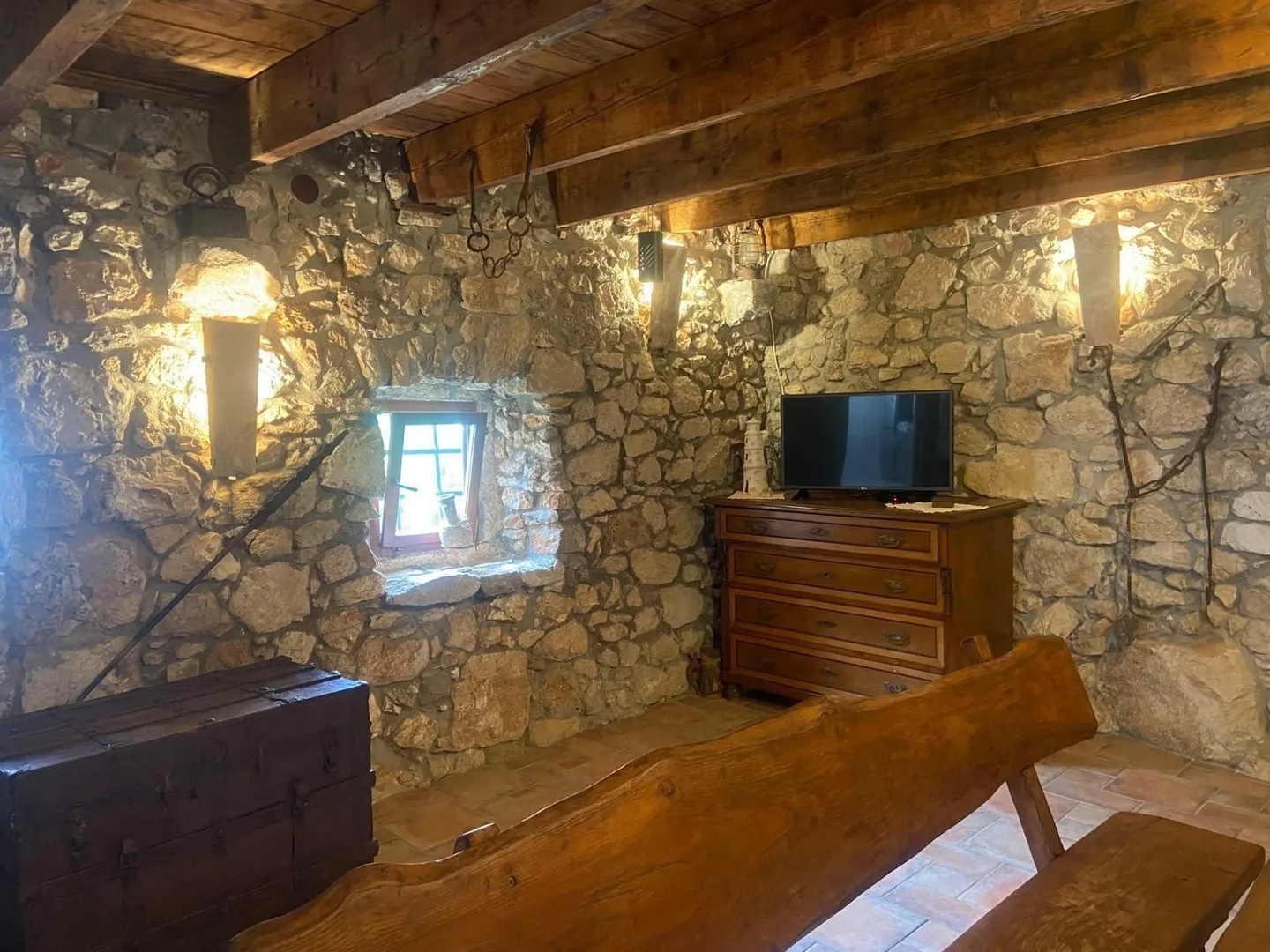 A small window in the stone wall above the chest of drawers