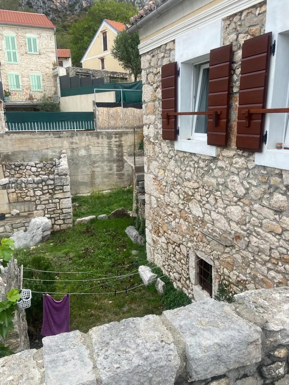 The village rooftops beyond the house wall and shutters